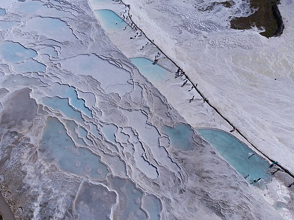 Travertine terraces in Pamukkale, Turkey. For many thousands of years, water saturated with minerals has left behind a precipitate of calcium salts, mainly from calcium carbonate, thereby forming unusual stepped geological forms. Recently, due to climate change, precipitation in this region has decreased, which caused many travertines to dry up. Photo by Maxim Bilovitskiy