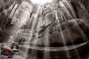 A monk paying homage to the Buddha statue of Wat Si Chum, Sukhothai Historical Park, Sukhothai Province Photograph: Yakuzakorat Licensing: CC-BY-SA-4.0