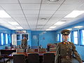 Two North Korean soldiers standing guard inside a JSA conference room, in front of the door leading to the South Korean side of the JSA. View from north to south.