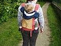 Un enfant sur le dos de sa mère dans un sac de portage