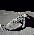 Astronaut Harrison Schmitt standing next to boulder during third EVA