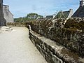 Banc de pierre faisant le tour, côté intérieur, du mur ceinturant l'enclos paroissial de l'église Saint-Raymond.