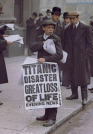 Colorised photo of Ned Parfett, best known as the "Titanic paperboy", holding a large newspaper banner advert about the sinking, standing outside the White Star Line offices at Oceanic House on Cockspur Street near Trafalgar Square in London SW1, April 16, 1912