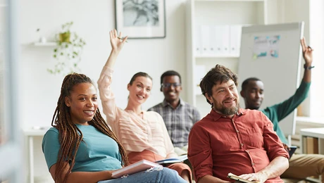 Decorative image of a small group of diverse adults engaged in a training class in a white room.