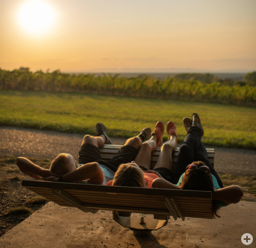 Weinbergen Relaxen Sitzbank mit drei Personen im Sportoutfit beim Sonnenuntergang anschauen