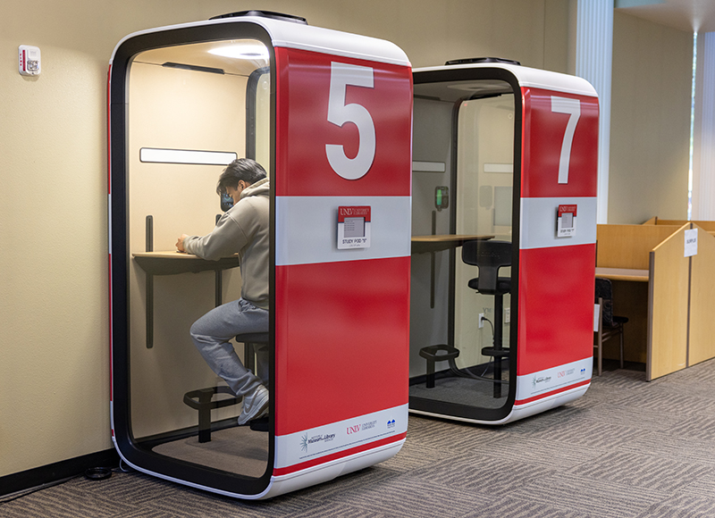 Two red and white study pods numbered 5 and 7 with a person working inside pod 5.