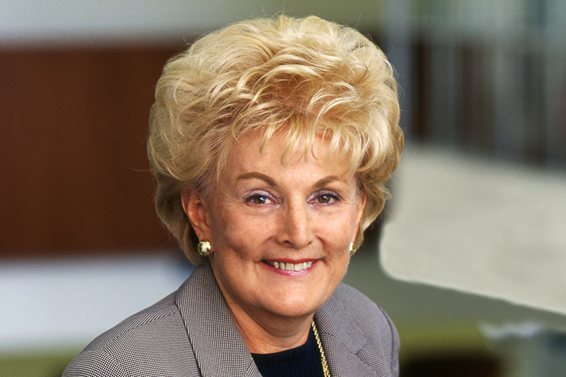 Smiling woman with short blonde hair in a grey blazer.