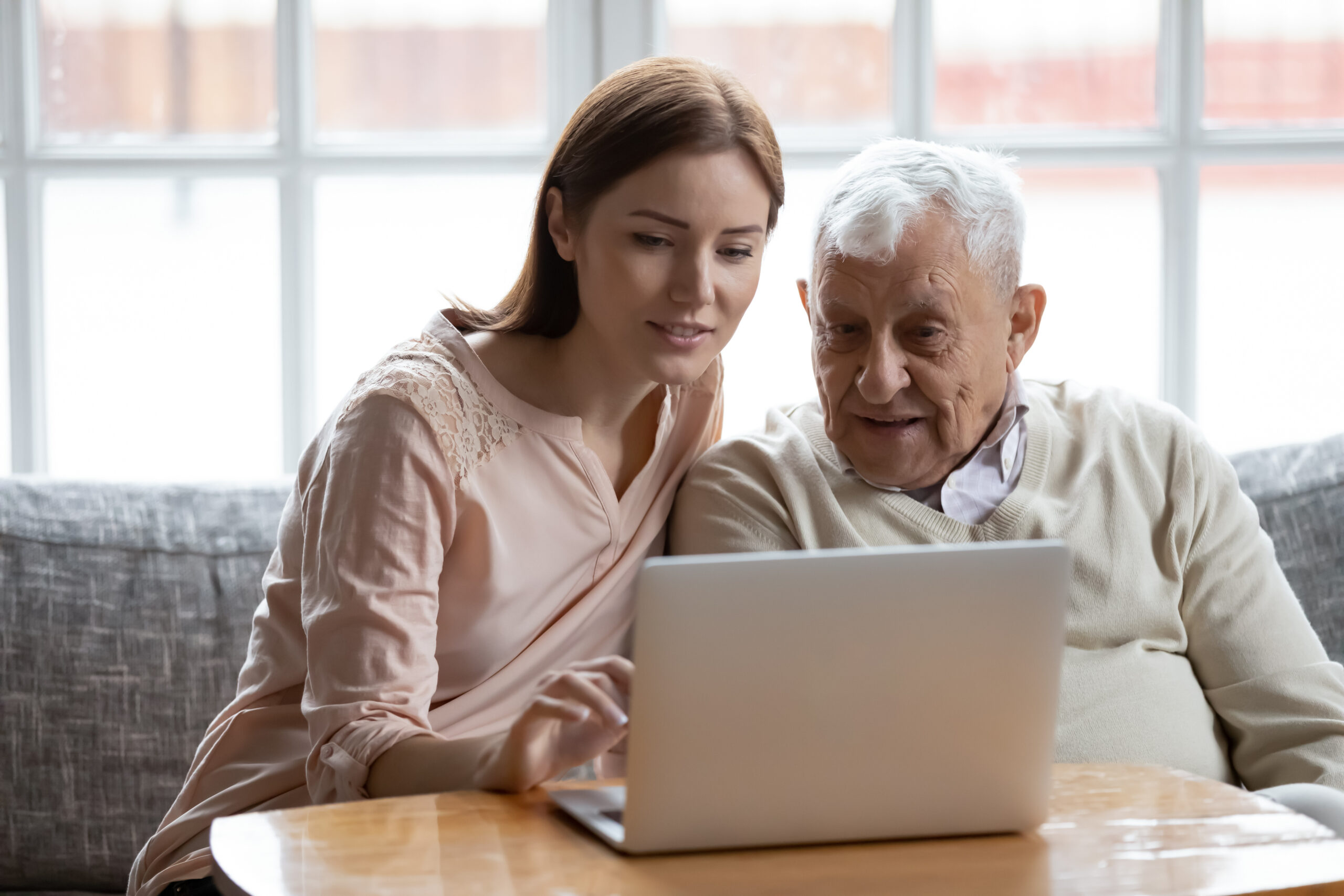 Grown-up daughter and older father choose books on a laptop on a table