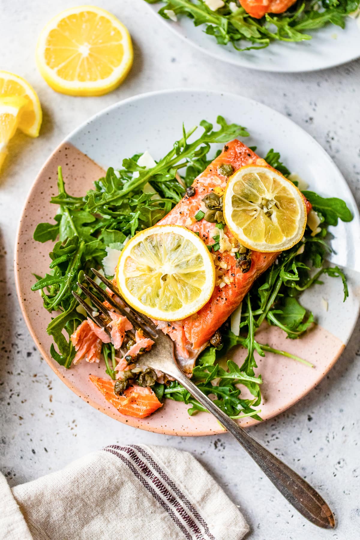 Baked Steelhead Trout with lemond and arugula on a plate