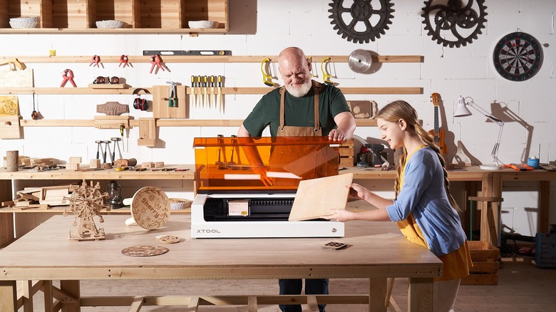 Two people using xTool S1 laser engraver on workbench