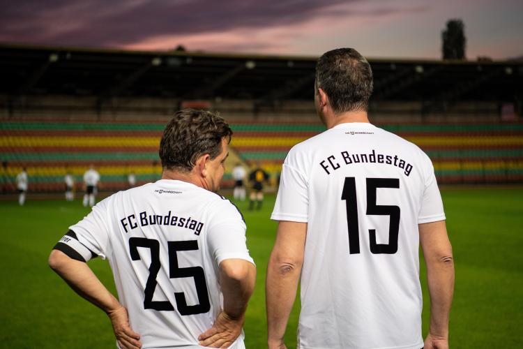 Two FC Bundestag soccer players on the sidelines.