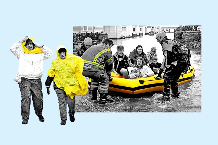 People in rain gear, alongside a rescue team helping flood victims into a yellow life raft.