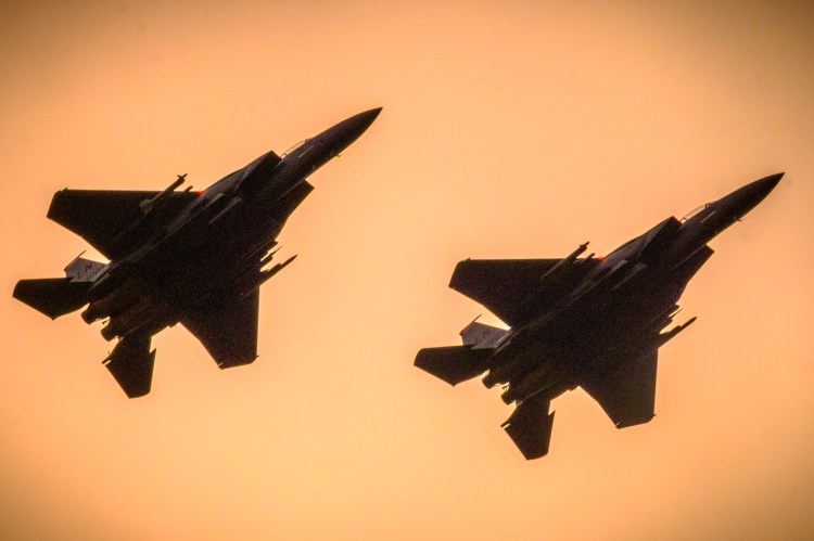 Silhouetted F-15 fighter jets in flight.