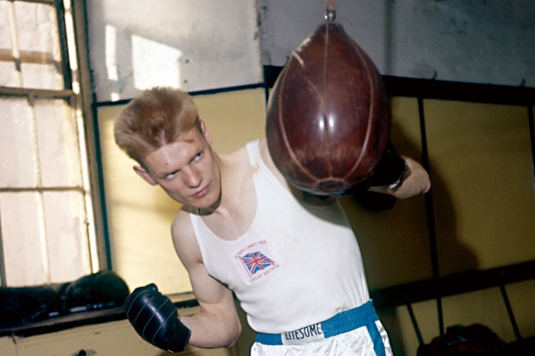 Boxer Dick McTaggart training with a punching bag.