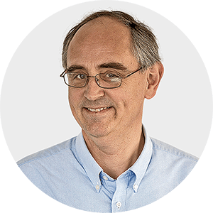 a man wearing glasses and a blue shirt smiles for the camera