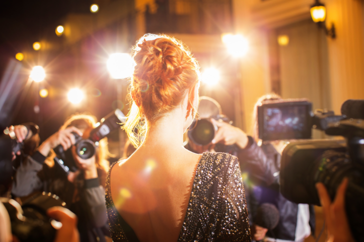 A glamorous woman poses for a crowd of photographers.